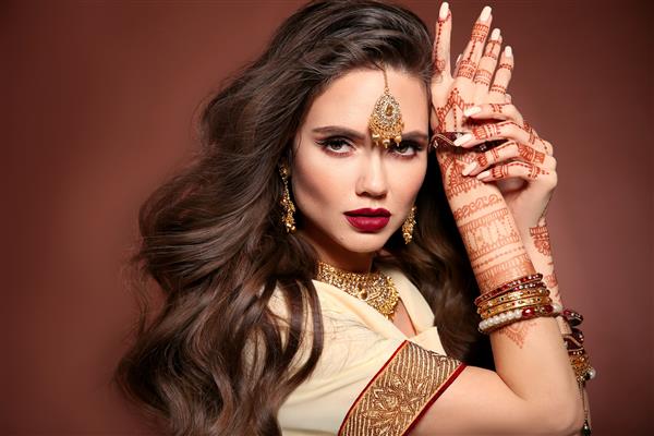 موی حالت دار پرتره زن زیبا با جواهرات هندی مدل سبزه جوان با ست جواهری طلایی سنتی هندی نقاشی مهندی حنا روی دست