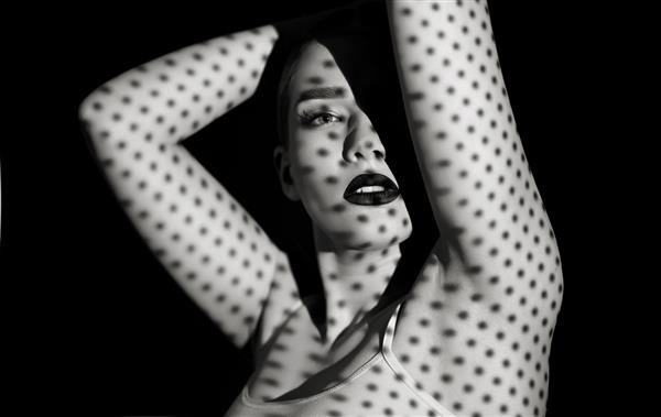 پرتره سیاه و سفید یک زن جوان زیبا با الگوی سایه روی صورت و بدنش به شکل دایره