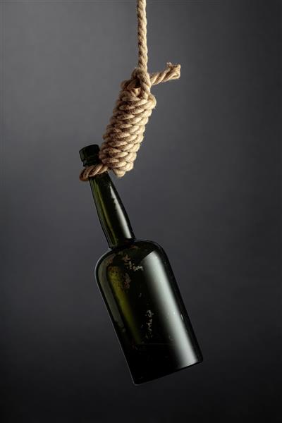 یک بطری قدیمی الکل در یک حلقه آویزان است تصویری مفهومی از موضوع اعتیاد به الکل افسردگی و خودکشی