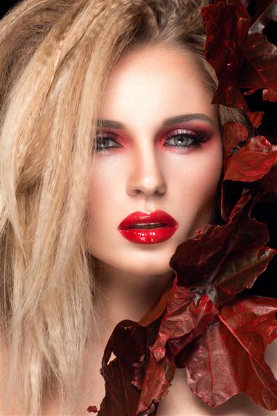 زن زیبا با لب ها و برگ های قرمز