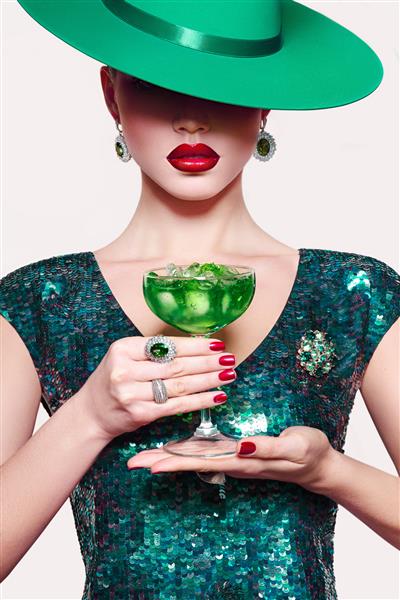 دختری با کلاه سبز با کوکتل در دست لباس مجلسی سبز یخ ابسنت