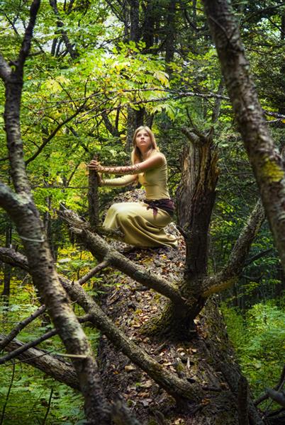 دختر بلوند لباس پوشیده در جنگلی جادویی قدم می زند