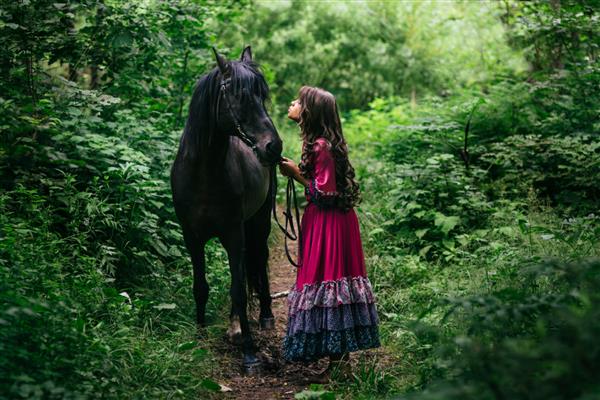کولی زیبا با لباس بنفش با اسب سیاه