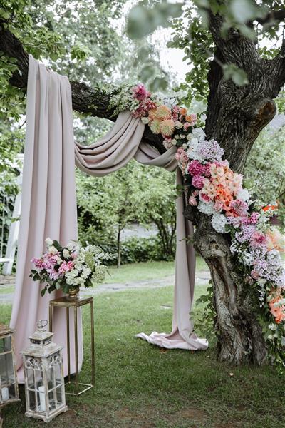 مراسم عروسی یک طاق عروسی بسیار زیبا روی درخت با گل های زیبا و تازه تزئین شده است شمع ها در نزدیکی آن ایستاده اند