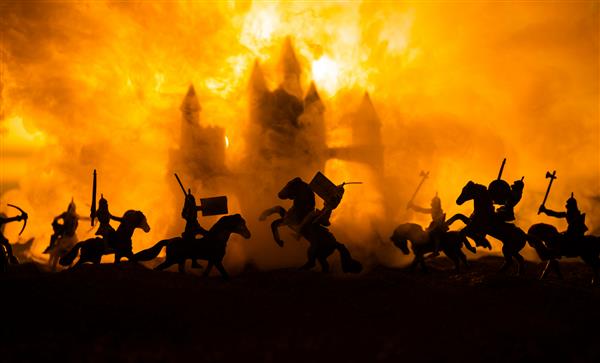 صحنه نبرد قرون وسطی با سواره نظام و پیاده نظام سیلوئت های فیگورها به عنوان اشیاء جداگانه جنگ بین جنگجویان در پس زمینه مه آلود غروب آفتاب تمرکز انتخابی