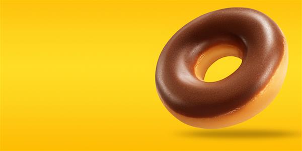 چیدمان خلاقانه از دونات شکلاتی در پرواز با فضای کپی در پس زمینه زرد و نارنجی مفهوم غذای شیرین