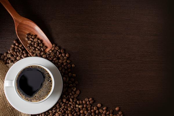 فنجان قهوه و دانه های قهوه روی یک تخته چوبی با فضای کپی برای متن