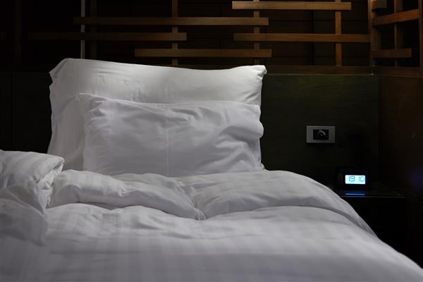 تخت خواب در اتاق هتل در تمیز کردن و آماده کردن اتاق برای مفهوم مشتری