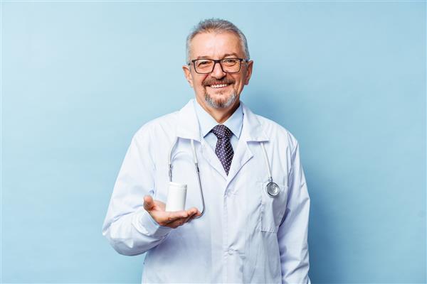 دکتر مرد قفقازی که بطری قرص را در پس زمینه سفید در دست دارد