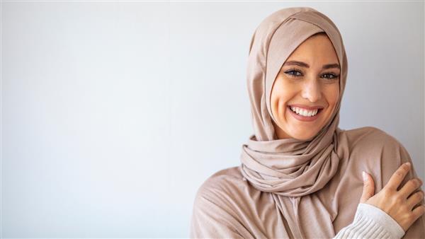 پرتره زن اسلامی در حال خندان دختر زیبای مسلمان ژست مدل زن مسلمان آسیایی زیبا در استودیو دیوار خاکستری پرتره زیبایی عرب
