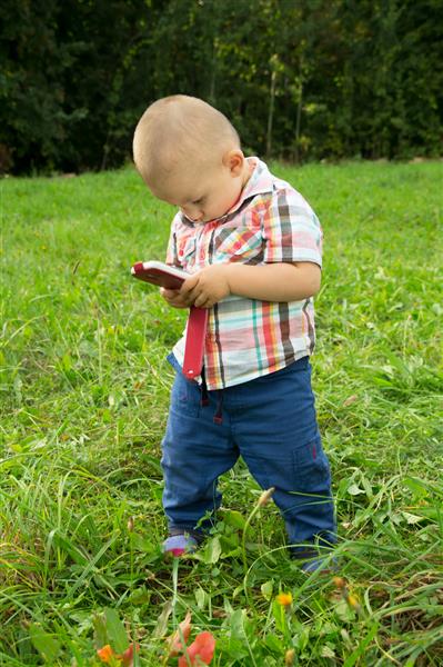 پسر بچه ای در حال بازی با تلفن در طبیعت