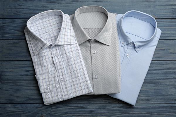 پیراهن‌های مردانه شیک روی پس‌زمینه چوبی آبی صاف