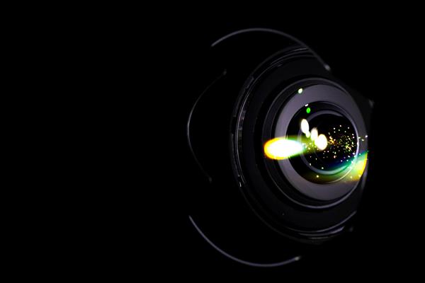 انعکاس لنزها نورهای شعله ور در شاتر عکس دوربین فیلمبرداری جدا شده در پس زمینه سیاه افکت فلاش اشعه نوری در تجهیزات عکاس