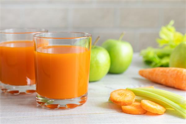 دو لیوان آب هویج کرفس و سیب سبز روی میز مفهوم رژیم غذایی تغذیه سالم غذا و کاهش وزن