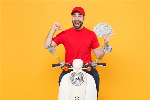 مرد تحویل‌دهنده با تی‌شرت کلاه قرمزی که در حال رانندگی با موتور اسکوتر است پول نقد جدا شده در استودیو پس‌زمینه زرد نگه می‌دارد