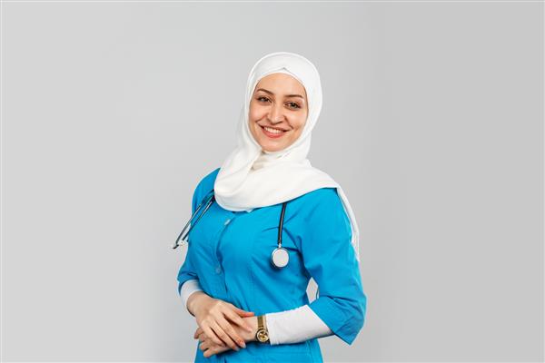 دکتر یا پرستار مسلمان مدرن زیبا با حجاب در زمینه خاکستری یونیفرم آبی مفهوم مراقبت های بهداشتی