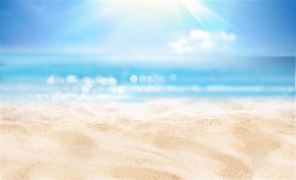 پس‌زمینه طبیعی تار و بدون تمرکز برای مفهوم تعطیلات تابستانی طبیعت ساحل تابستانی گرمسیری با پرتوهای نور خورشید ساحل شنی سبک آب اقیانوس در برابر آسمان آبی می درخشد