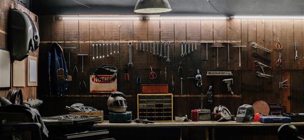 صحنه کارگاه ابزار قدیمی آویزان به دیوار در کارگاه قفسه ابزار در برابر میز و دیوار سبک گاراژ قدیمی