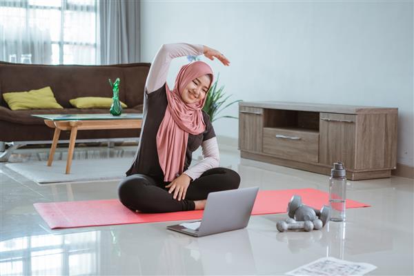 زن مسلمان در حال انجام ژیمناستیک در خانه