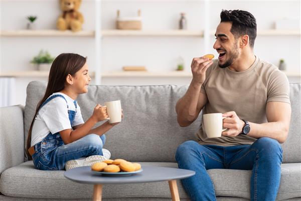 زمان میان وعده پرتره دختر و مردی شاد که فنجان در دست دارند قهوه و چای می نوشند کلوچه می خورند و به یکدیگر نگاه می کنند پدر و دختر در حال صحبت روی کاناپه در اتاق نشیمن