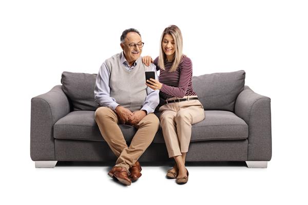 پیرمرد و زن جوانی روی مبل نشسته اند و به تلفن همراه جدا شده در پس زمینه سفید نگاه می کنند