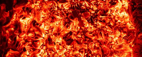 نمای جزئیات بالای سر و پس‌زمینه زغال‌سنگ چوبی قرمز داغ در منقل کباب‌پز یا آتش‌دان در شب تاریک جرقه های گرمای جهنمی زیبا که در اجاق گاز می درخشند