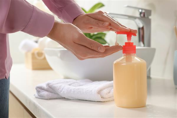 زن با استفاده از پخش کننده صابون مایع در حمام نمای نزدیک