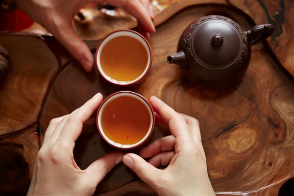 ست چای با نمای بالا میز چوبی برای پس زمینه مراسم چای زن و مردی که یک فنجان چای در دست دارند