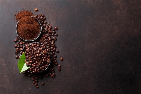 دانه های قهوه و پودر آسیاب شده در زمینه سنگ نمای بالا با فضای کپی برای متن شما