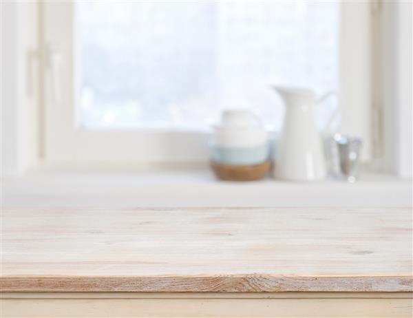 صفحه میز چوبی در پس زمینه پنجره آشپزخانه تار