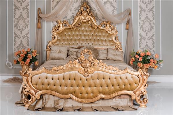 اتاق خواب لوکس در رنگ های روشن با جزئیات مبلمان طلایی تخت سلطنتی دو نفره راحت در فضای داخلی کلاسیک زیبا