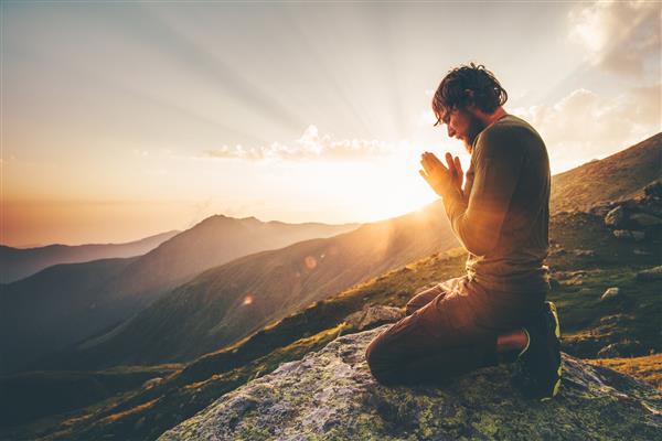 مردی که به تنهایی در غروب کوه ها دعا می کند سفر سبک زندگی آرامش معنوی مفهوم عاطفی تعطیلات در فضای باز هماهنگی با چشم انداز طبیعت