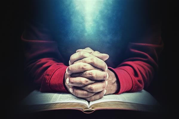 دست در دعا بر سر یک کتاب مقدس