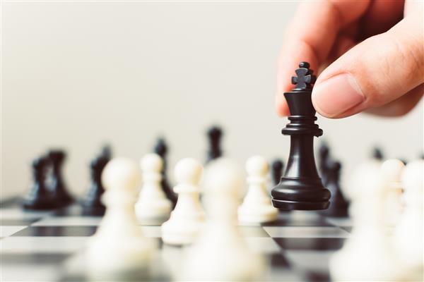 طرح استراتژی پیشرو برای مفهوم رهبر رقابت تجاری موفق دست بازیکن شطرنج بازی روی تخته با قرار دادن پیاده سیاه فضای کپی برای متن خود