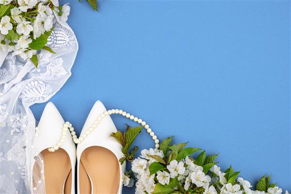کفش های سفید عروس و شکوفه های گیلاس در بهار پس زمینه جشن عروسی مهره های سفید چادر سجاف لباس عروس