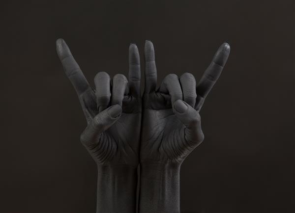 ژست بز در پس زمینه تیره دست سیاه در حال انجام نماد سنگ دست ها در کنسرت راک ستاره موسیقی مفهوم هوی متال آهن سیاه