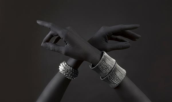 دست‌های زن سیاه‌پوست با جواهرات مختلف نقره‌ای دستبندهای شرقی روی دست مشکی جواهرات نقره و لوازم جانبی لوکس در زمینه مشکی مفهوم هنری مد بالا