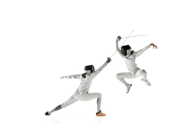 دختران نوجوان در لباس‌های شمشیربازی با شمشیر در دست جدا شده در پس‌زمینه سفید استودیو مدل های زن جوان در حال تمرین و آموزش در حرکت اکشن فضای کپی ورزش جوانان سبک زندگی سالم
