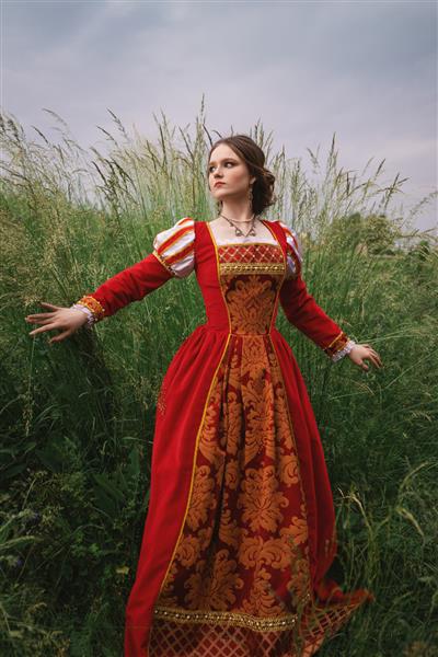 زنی با لباس قرون وسطایی قرمز که در چمن ایستاده است