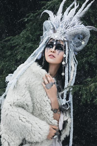 زن زیبا با آرایش فانتزی و تاجی که در برف می بارد