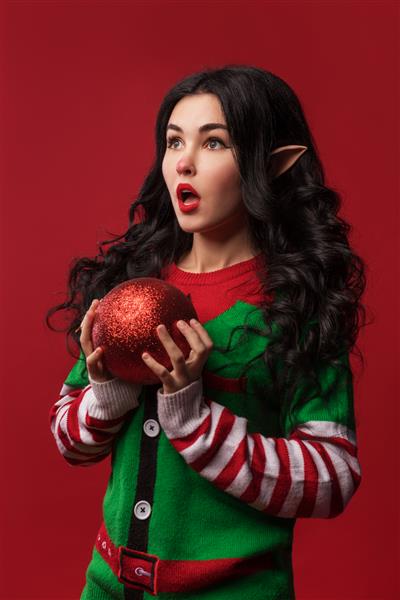 زنی با لباس جن و گوش های الف با توپ کریسمس
