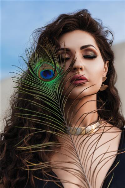 نمای نزدیک از یک زن زیبا با پر طاووس