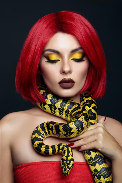زن زیبا با موهای قرمز و مار پیتون زرد به دور گردنش آرایش چشم زیبایی روشن حرفه ای رژلب زرد قرمز شرابی