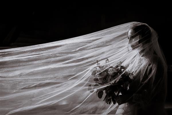 نمای کناری عکس سیاه و سفید عروس با دسته گل در دست و چادر بلند