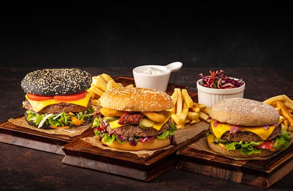 سه چیزبرگر آبدار گوشت گاو خانگی روی تخته چوبی مجموعه ای از همبرگر با گوشت گاو و پنیر در تیره