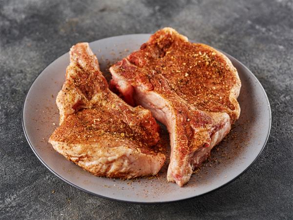 راسته گوشت خوک خام تازه با استخوان چاشنی شده با ماریناد خشک تهیه شده برای bbq
