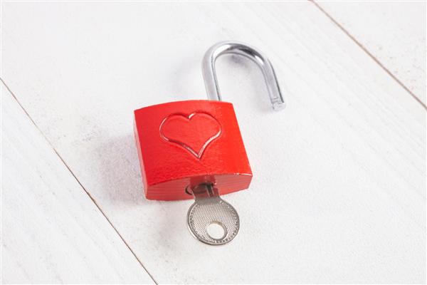 قفل قرمز با قلب برای یک روز خاص مانند ولنتاین تولد عروسی یا عشق جدا شده بر روی پس زمینه چوبی سفید