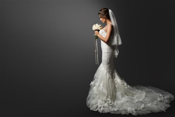 لباس عروسی عروس با لباس مجلسی سفید مدل مد عروس دسته گل در دست نمایه نمایه روی پس‌زمینه سیاه فضای کپی
