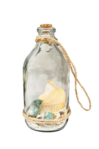 صدف های دریایی و ماسه در بطری کریستالی جدا شده روی سفید