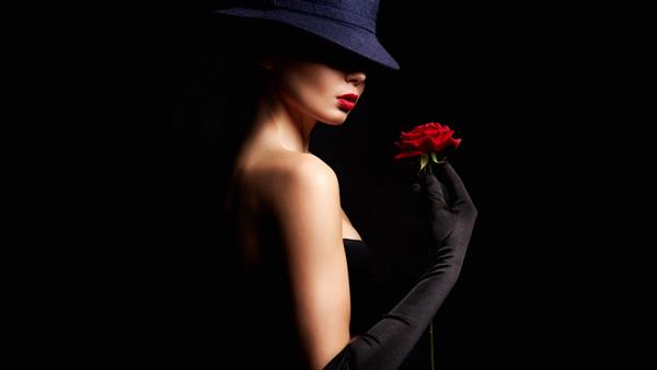 زن جوان زیبا با کلاه و گل دختر دوست داشتنی دستکش پوشیده بود و رز قرمز در دست داشت پرتره زیبایی
